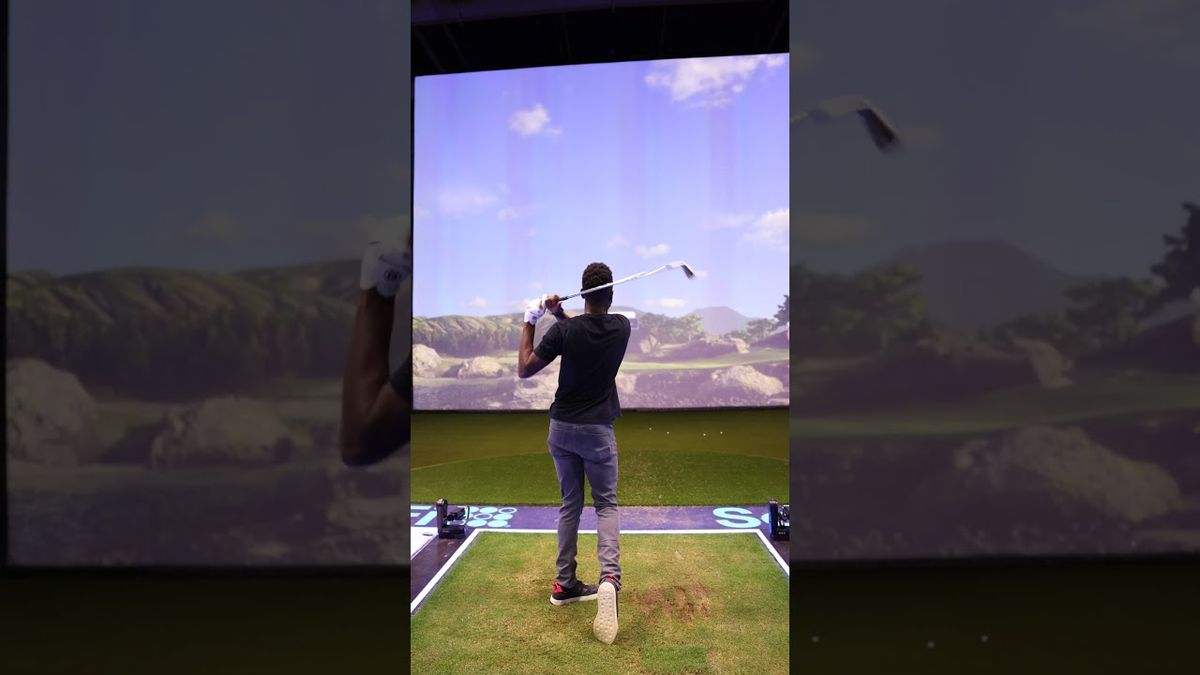 Für das Video-Thumbnail von "The World's Largest Golf Simulator" von Marques Brownlee könnte der Alt-Text folgendermaßen lauten: "Marques Brownlee steht in einem großen Raum mit einem riesigen Bildschirm, der einen Golfplatz zeigt. Er hält einen Golfschläger in der Hand und lächelt in die Kamera.