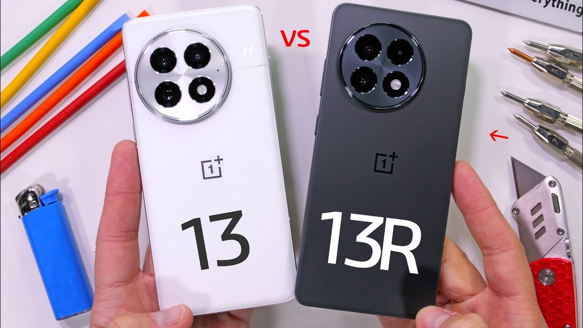 Video thumbnail showing two smartphones, the OnePlus 13 and OnePlus 13r, placed side by side on a wooden surface. The phones are being subjected to a durability test, with visible scratches and marks on their screens. A hand holding a metal tool is positioned above the phones, indicating ongoing testing. The background is blurred, focusing attention on the phones and the tool.